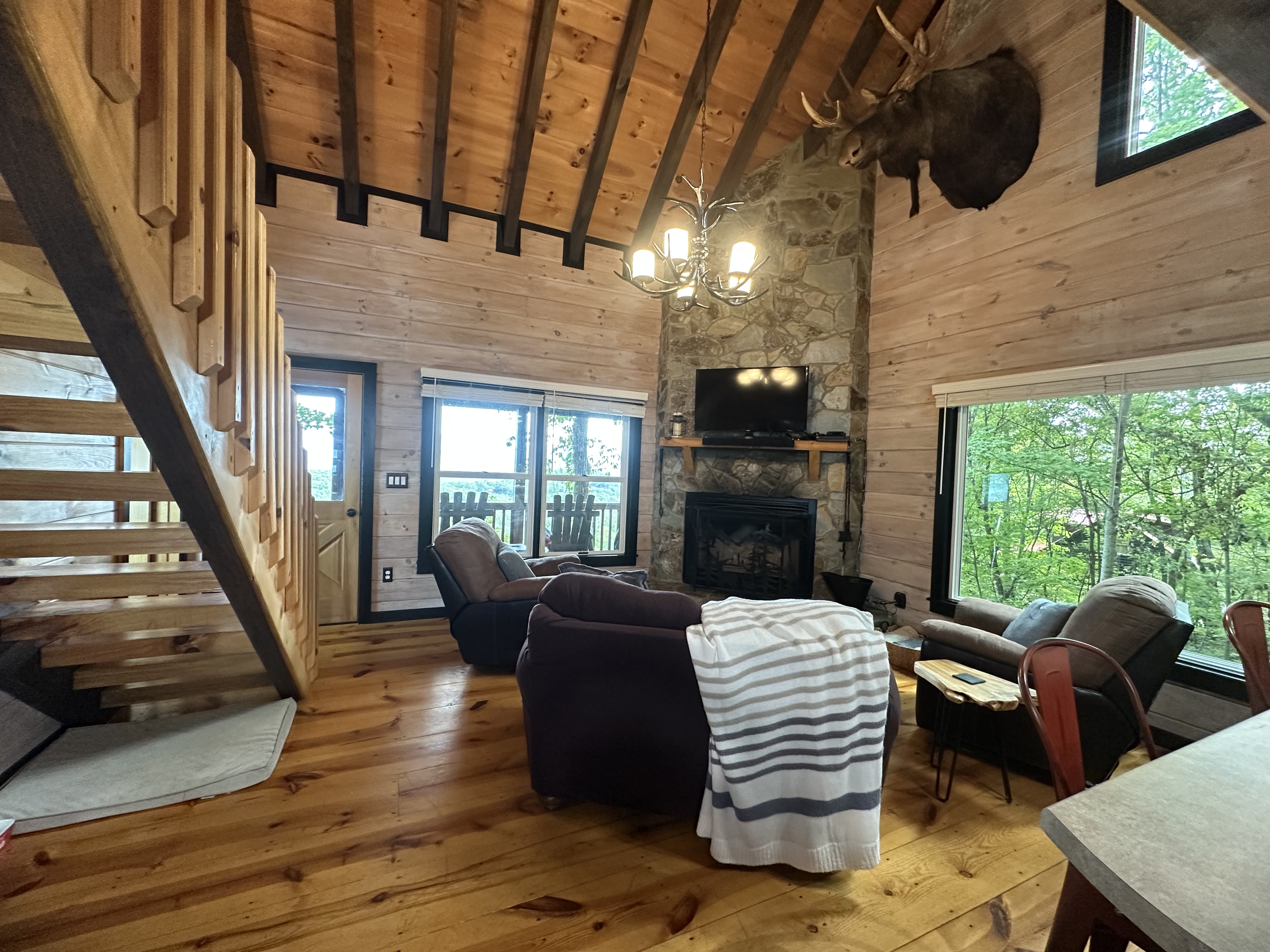 The main living room brings together vaulted wood ceilings, mountain light, and the stone fireplace.